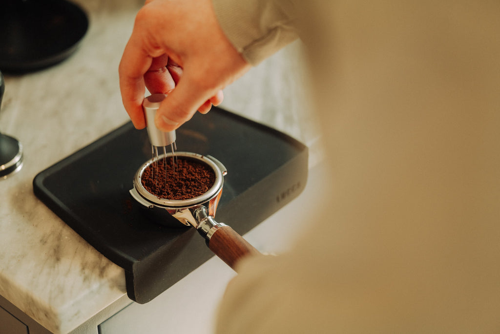 barista using a WDT tool with a bottomless portafilter